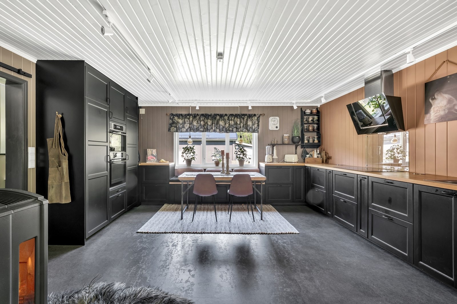 Kjøkkeninnredning med profilerte fronter. Malte flater over heltre benk med nedfelt stålkum med ett-greps blandebatteri. Integrert kjøleskap, fryser, oppvaskmaskin, dampovn, koketopp og komfyr. Galleribilde