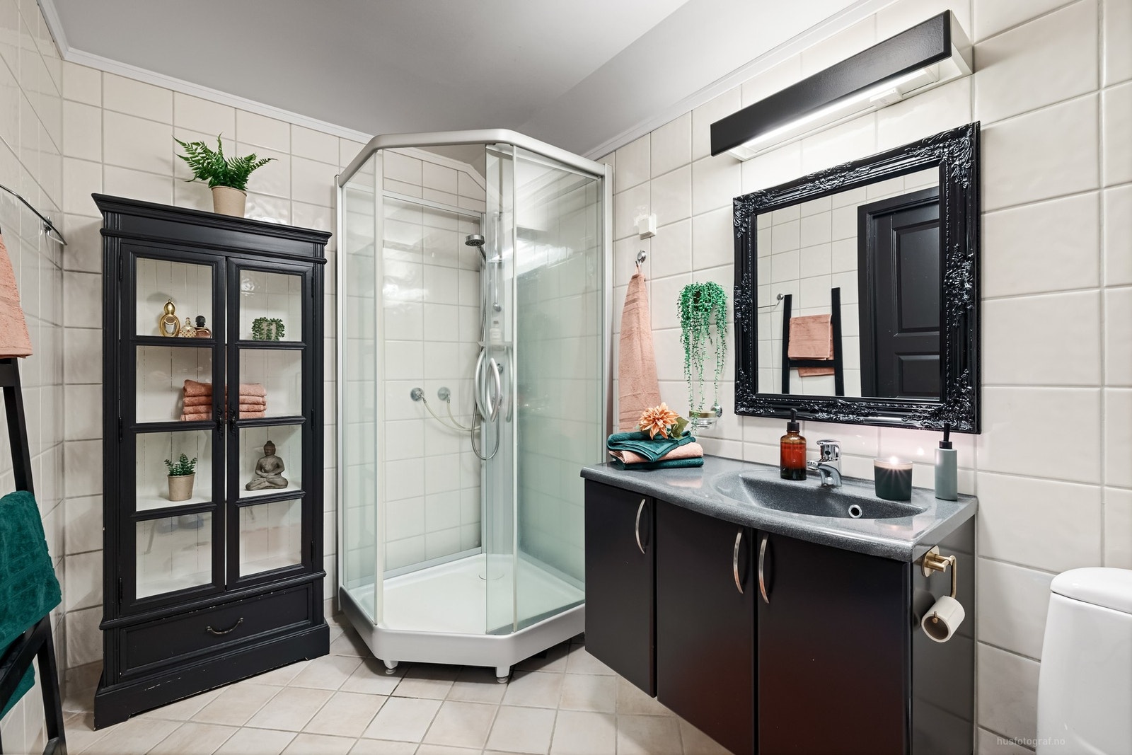 Flislagt bad med dusjkabinett, toalett og servant med underskap. Galleribilde