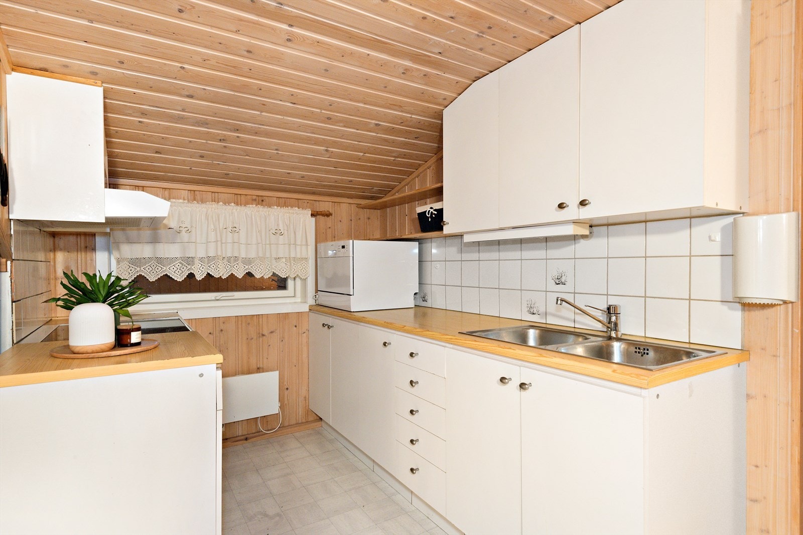 Kjøkkenet på hybelen er smått, smart og praktisk. Av hvitevarer følger det med oppvaskmaskin, komfyr og kjøl og fryseskap. Galleribilde