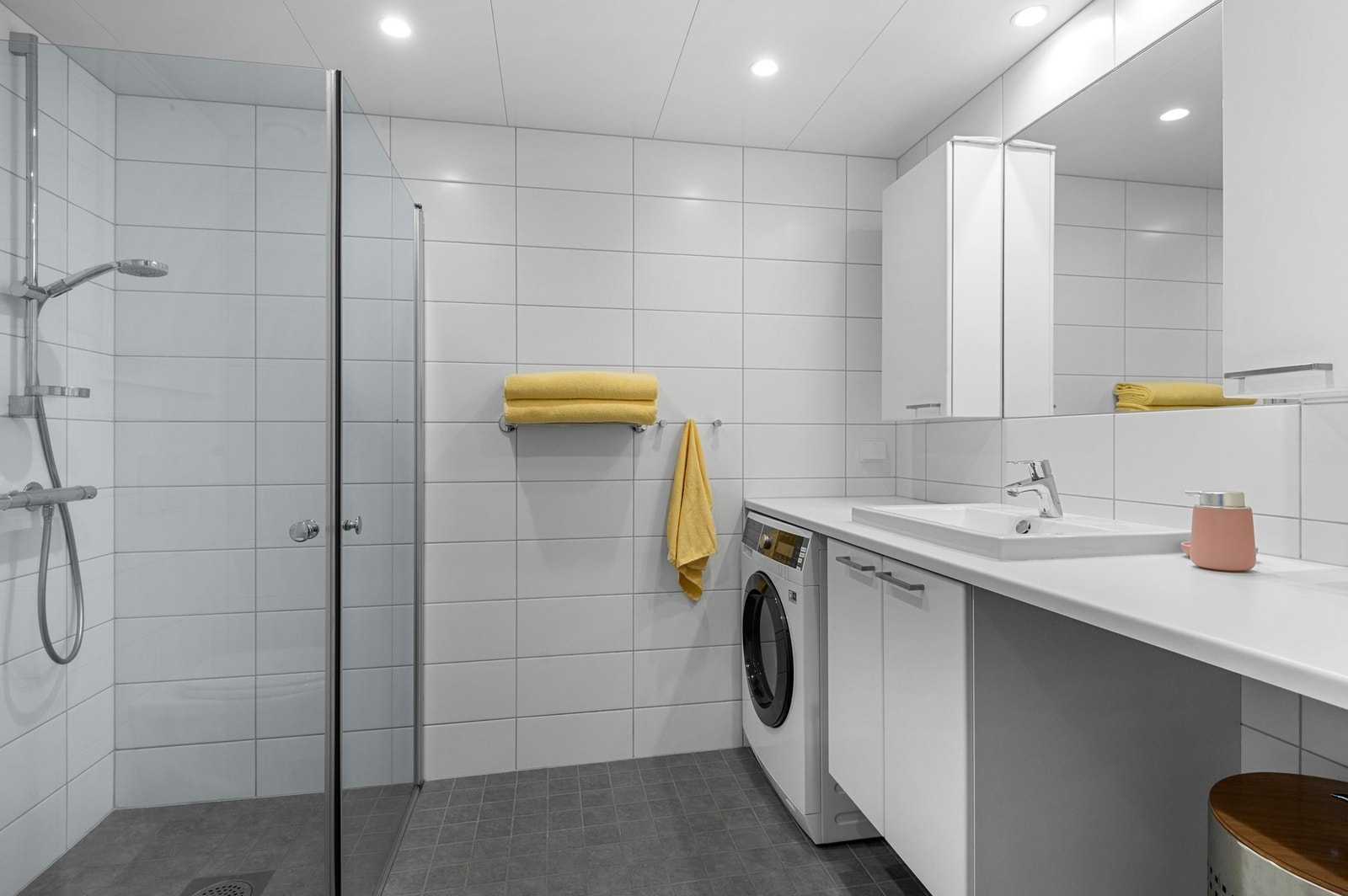 Badet består av vegghengt toalett, dusjhjørne, opplegg for vaskemaskin og moderne baderomsinnredning. Galleribilde