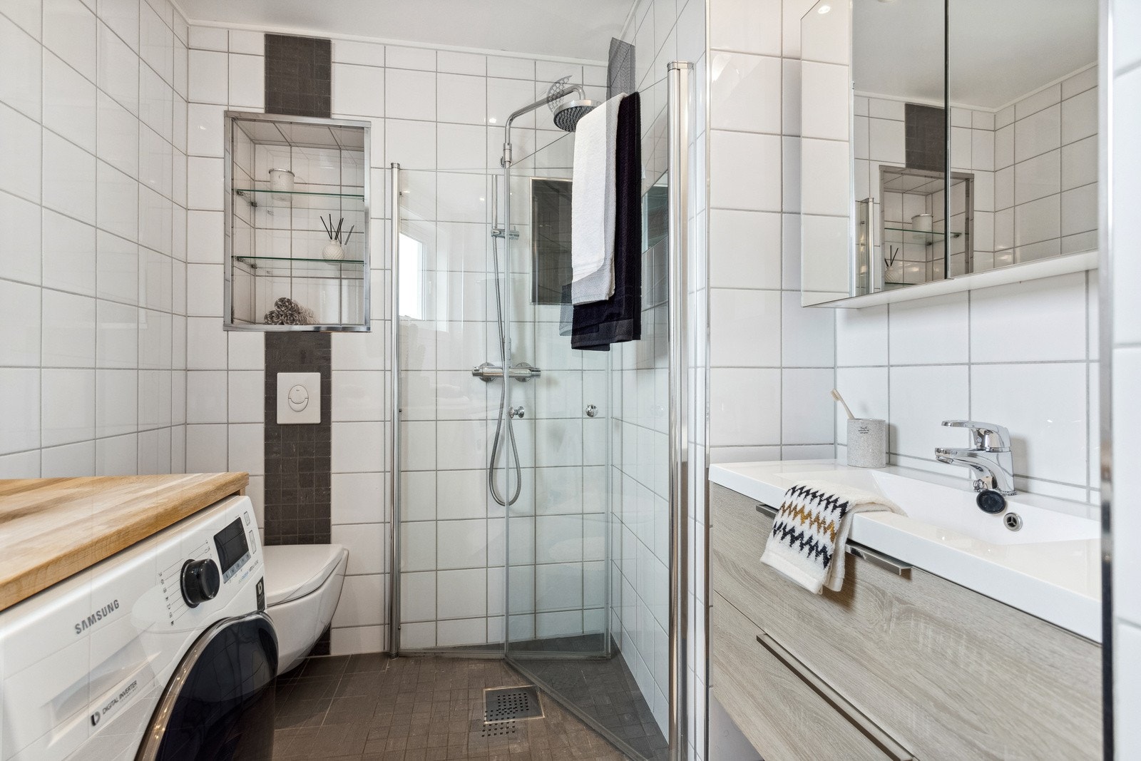 Fint bad utstyrt med vegghengt toalett, servantinnrening, dusj med innfellbare glassdører, samt opplegg for vaskemaskin. Galleribilde