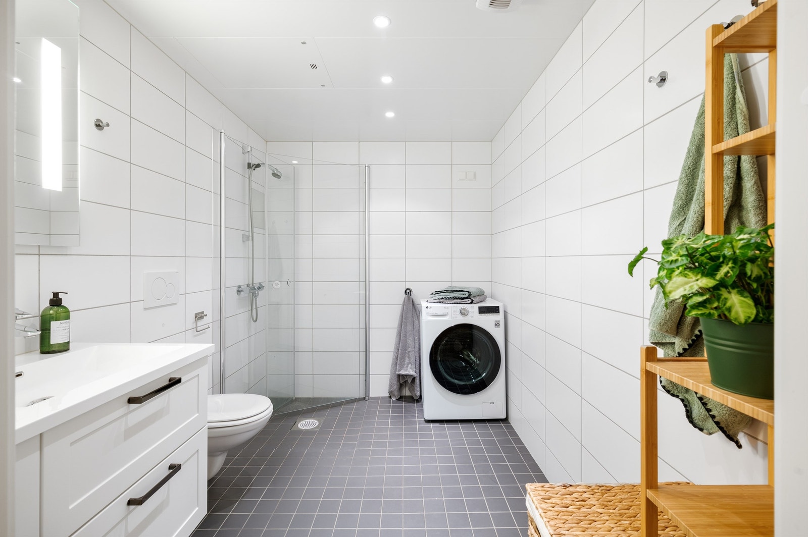 Badet er innredet med stor servantinnredning, speil med integrert lys, hjørnedusj med innfellbare dører, samt opplegg for vaskemaskin og tørketrommel. Galleribilde