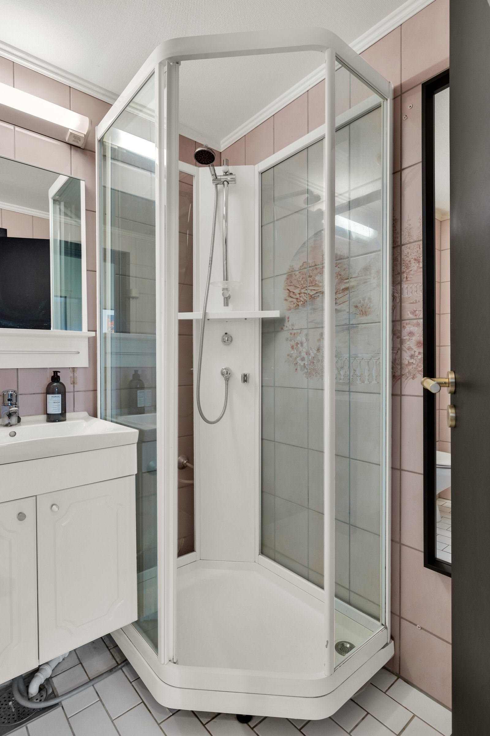 Badet har toalett, dusjkabinett og innredning med profilerte skapfronter, heldekkende servant og speil med belysning i overkant Galleribilde