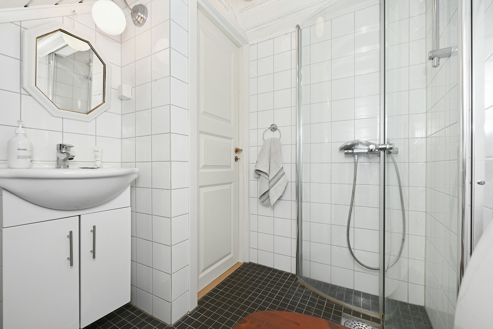 Badet har flislagte vegger og inneholder en innredning med nedfelt servant, en dusjnisje med innfellbare vegger og et gulvfestet toalett. I Galleribilde