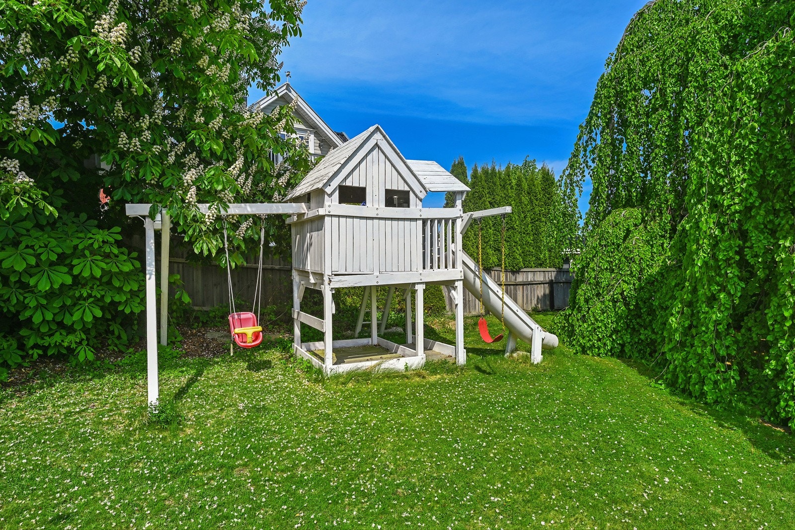 Tomten er pent opparbeidet med en blanding av gressplen, forskjellige typer beplantning og vakre trær. Galleribilde