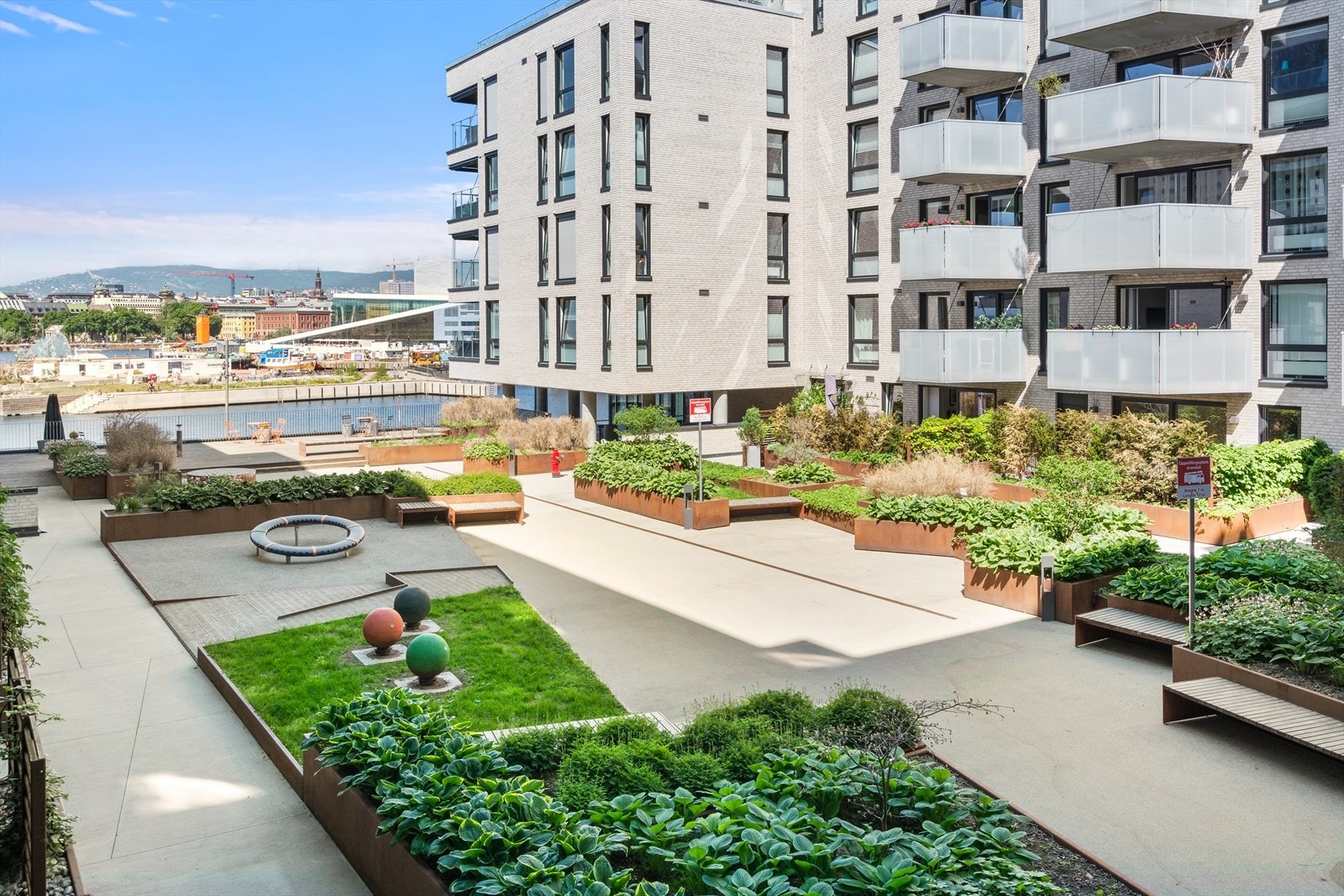 Pent opparbeidet bakgård med lekeapparater, beplantning, sittegrupper m.m. Galleribilde