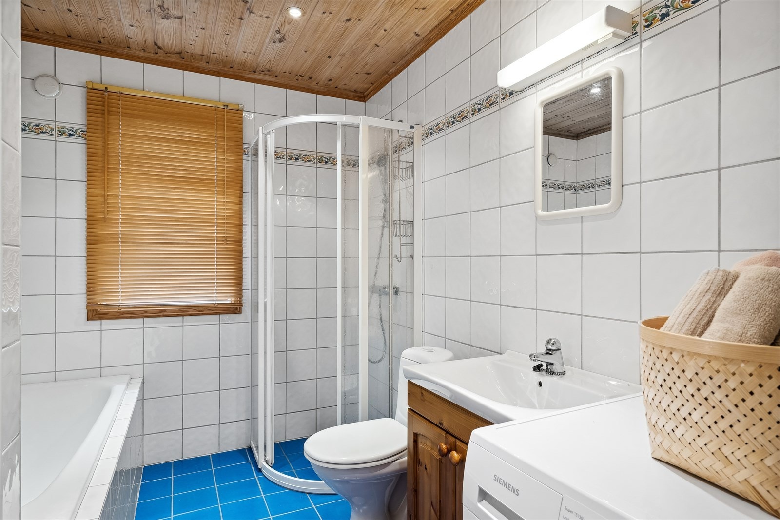Vaskeservant i skapinnredning, toalett, dusjvegger i glass og badekar, samt opplegg for vaskemaskin. Galleribilde