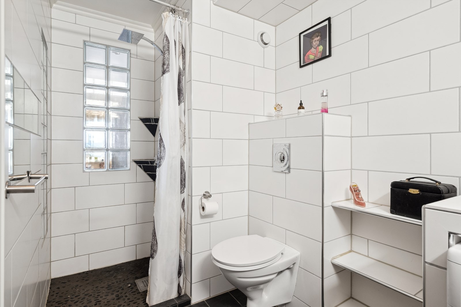 Baderom inneholder dusjsone, vegghengt toalett, opplegg for vaskemaskin og vask under innredet speil. Videre rikelig med hylleløsninger. Galleribilde