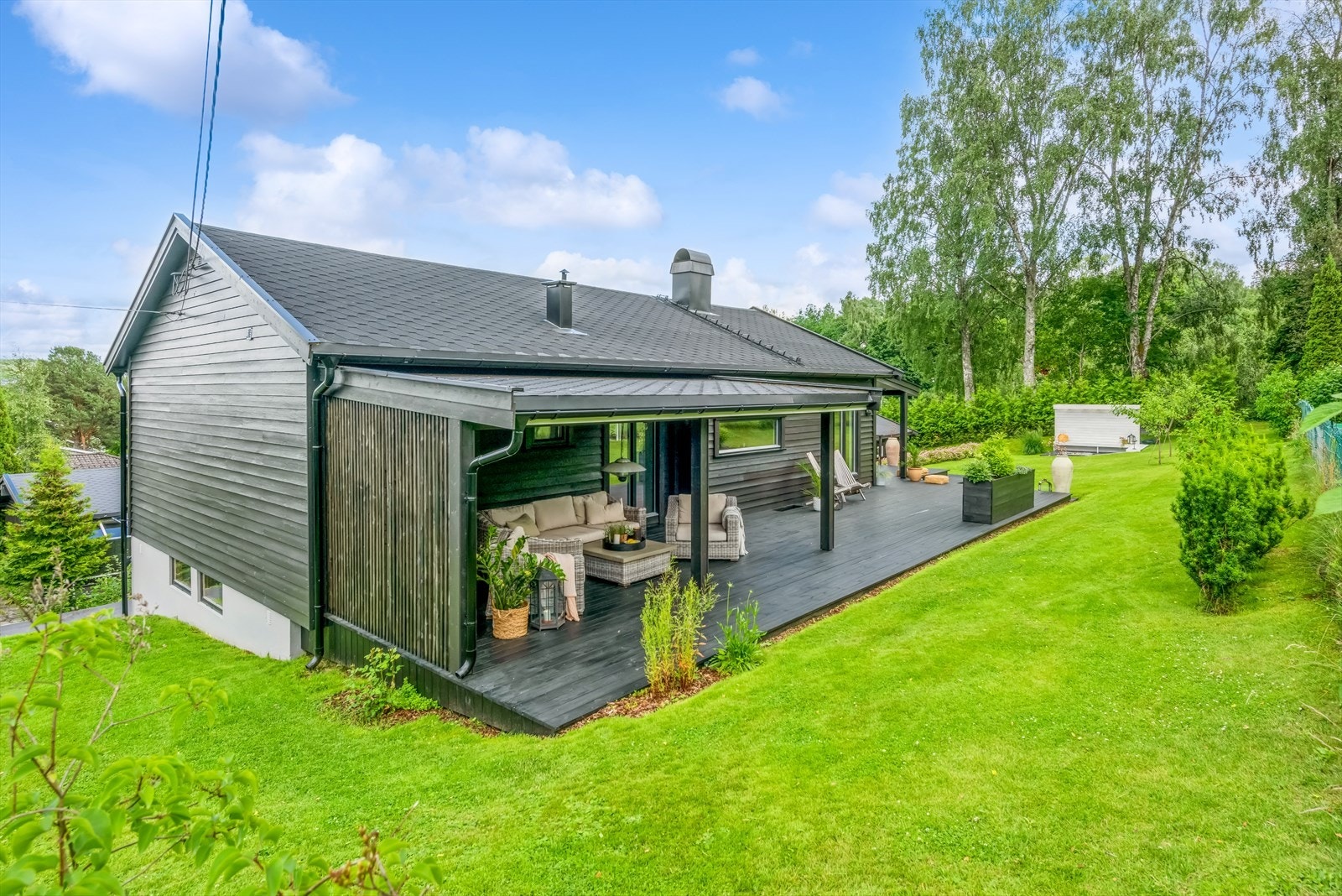 Veranda/terrassen strekker seg rundt boligen, med god plass til utemøblement. Galleribilde