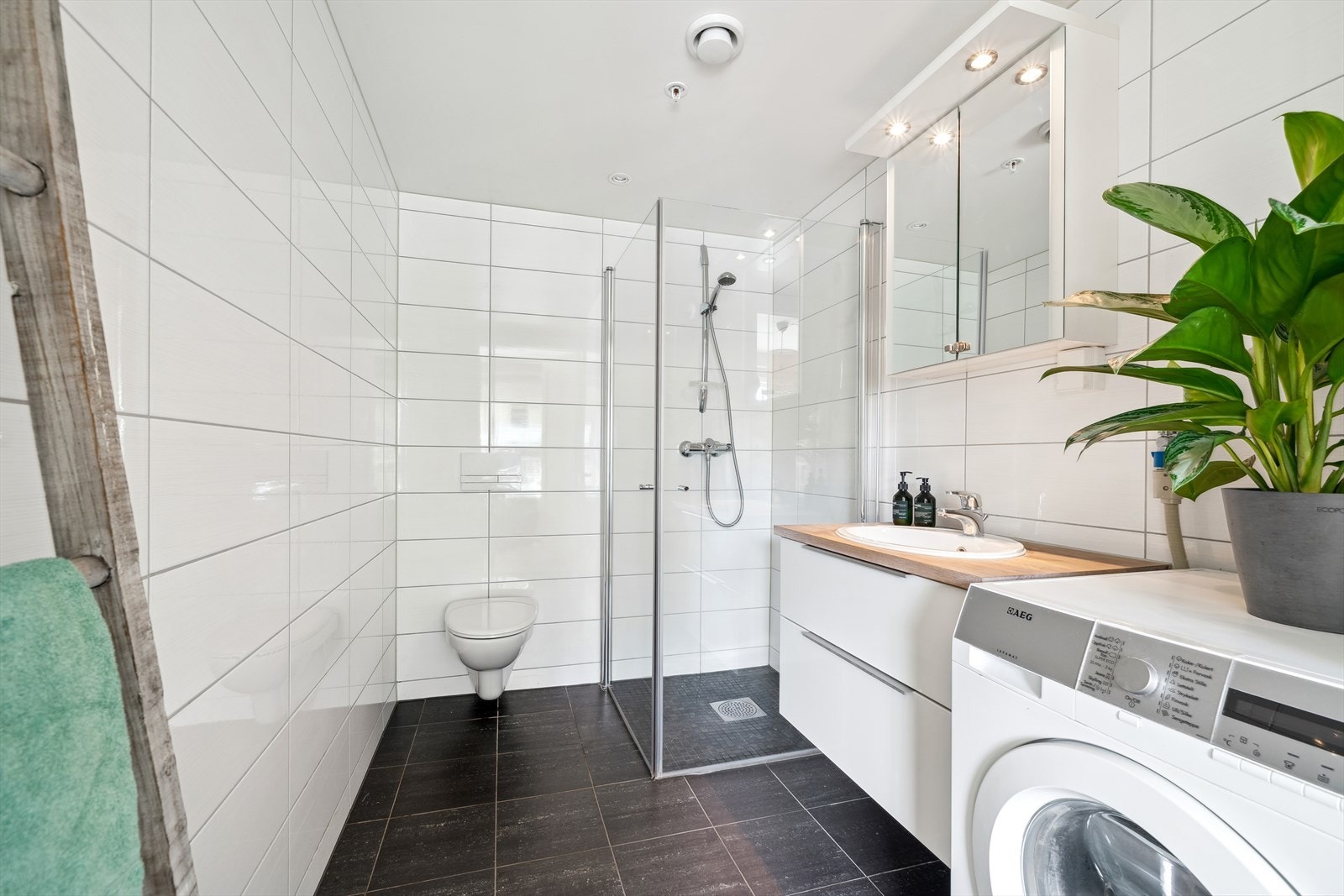 Badet er innredet med dusjhjørne, servant i innredning og vegghengt toalett. Det er opplegg for vaskemaskin, downlights i tak og vannbåren gulvvarme Galleribilde