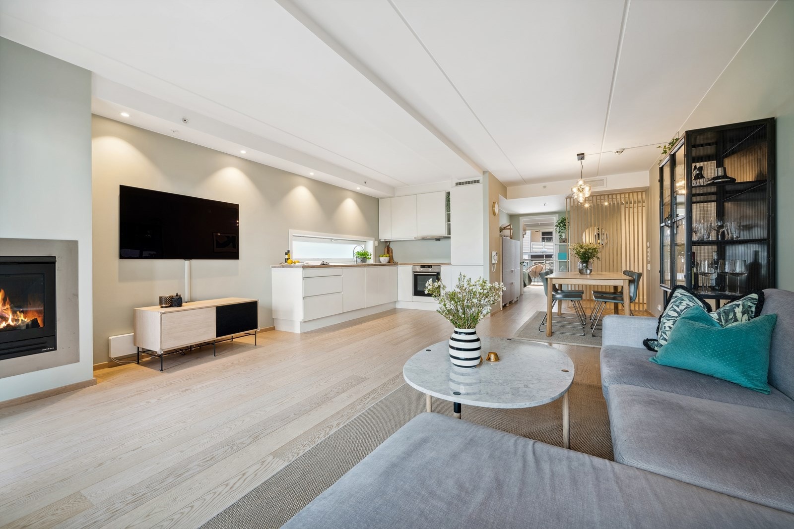 Romslig og lys stue med naturlige soner for sofahjørne og spisebord. Galleribilde