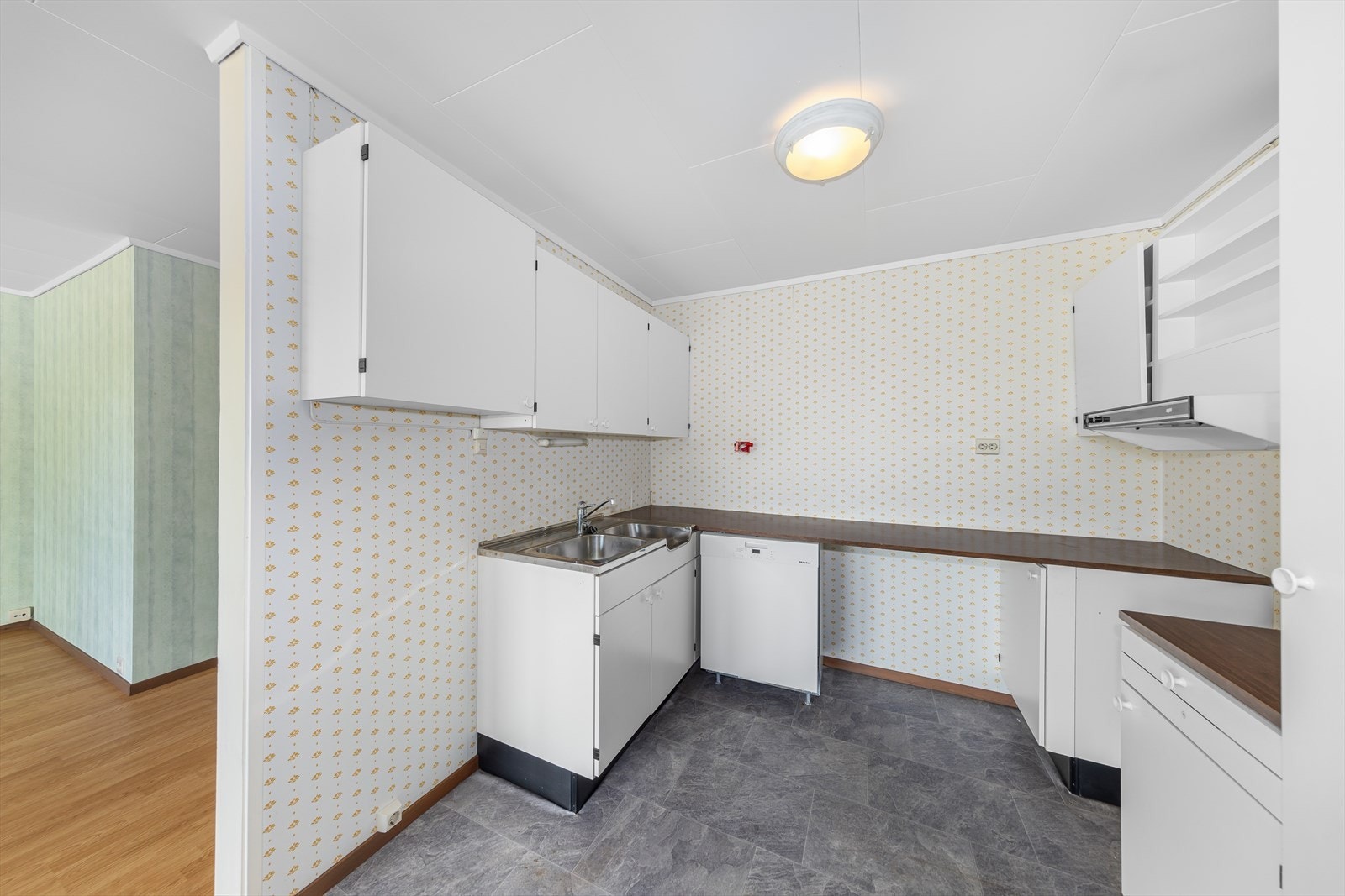 Kjøkkenet har en eldre, enkel innredning med glatte fronter, laminert benkeplate og en frittstående oppvaskmaskin som medfølger. Galleribilde