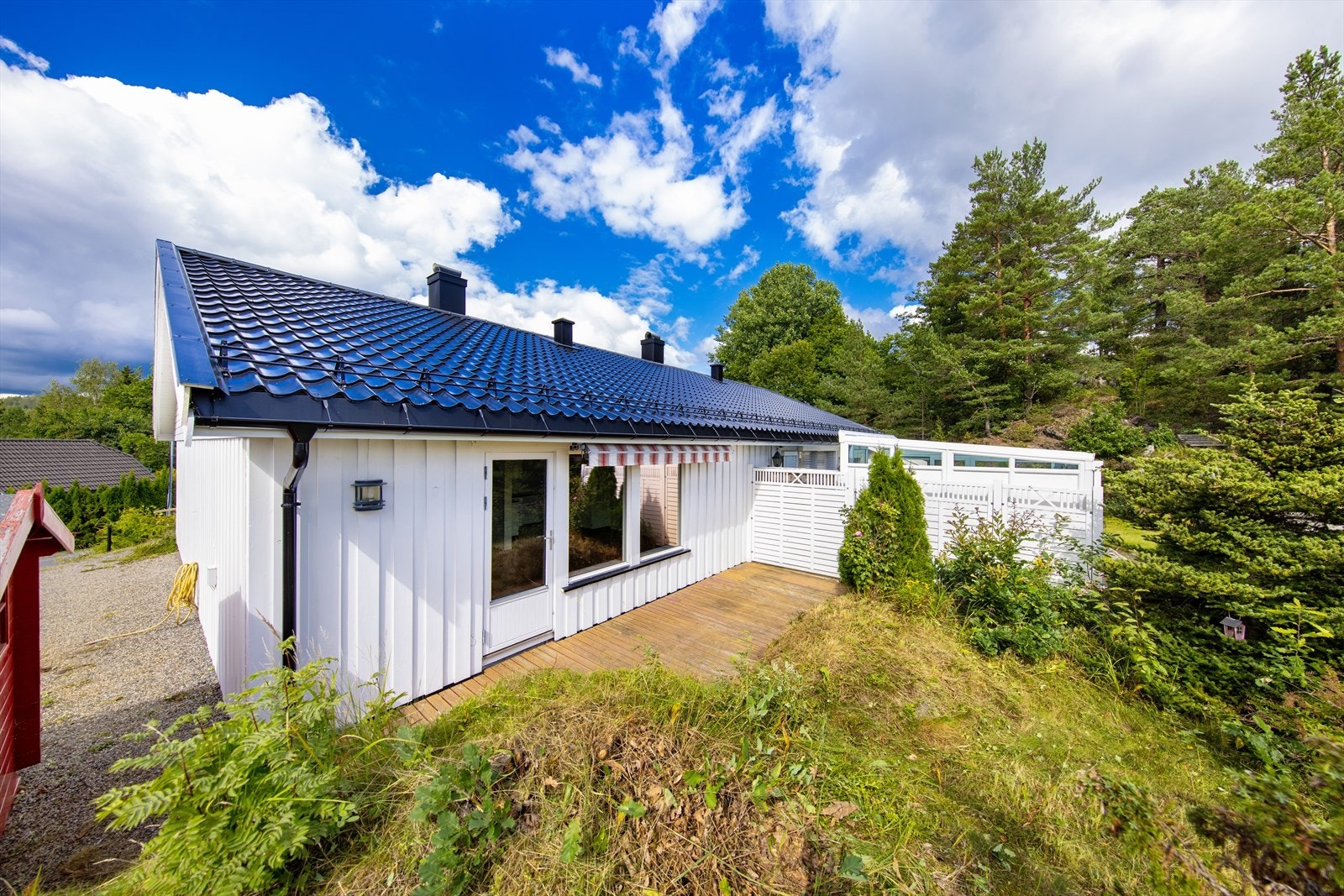 Sørøstvendt uteplass med utgang fra stuen. Uteplassen har terrase og ellers naturtomt. Galleribilde