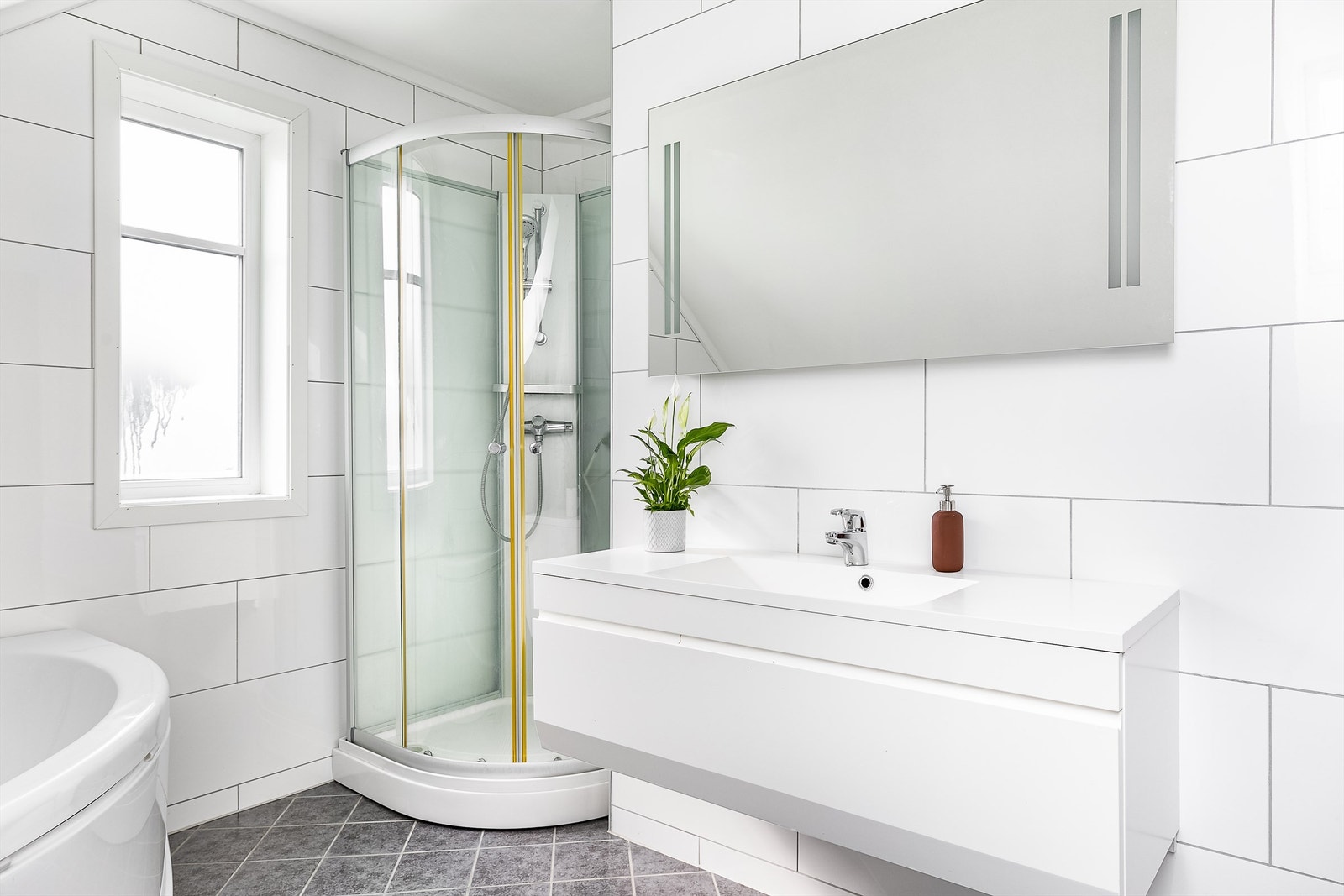 Badene er utført med like fliser på gulv og vegger samt baderomsmøbler i samme serie. Galleribilde