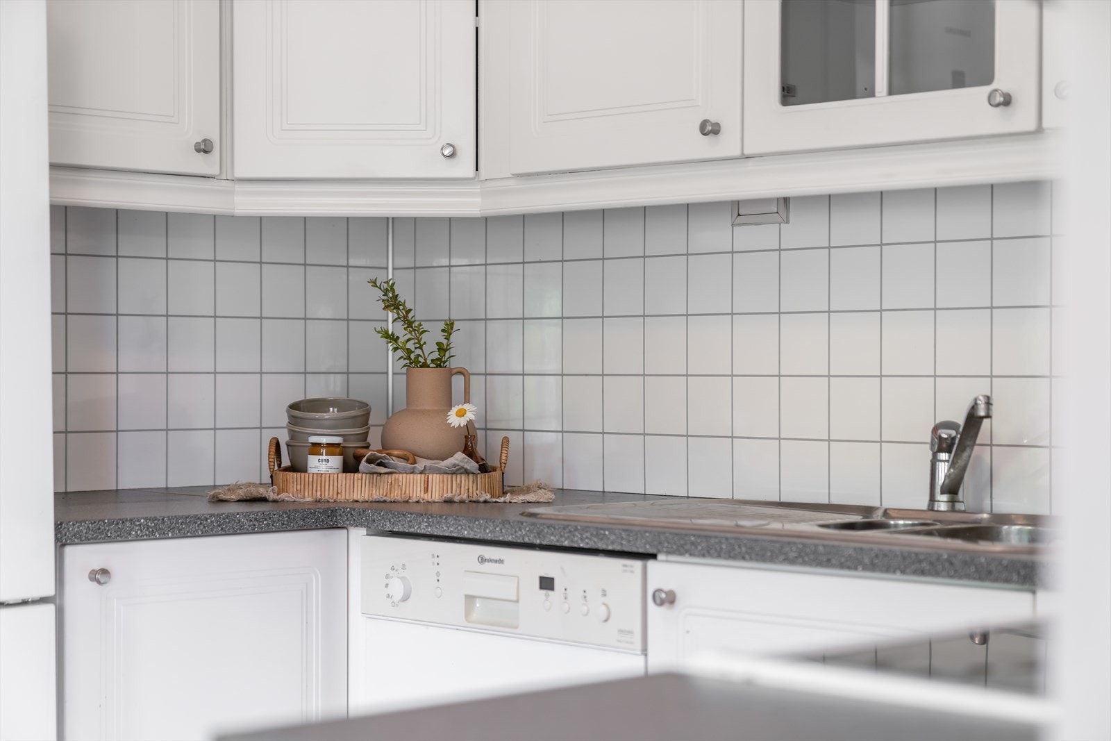 Kjøkkenplater på vegg over laminat benkeplate med nedfelt oppvaskkum med liten skyllekum og ett-greps blandebatteri Galleribilde