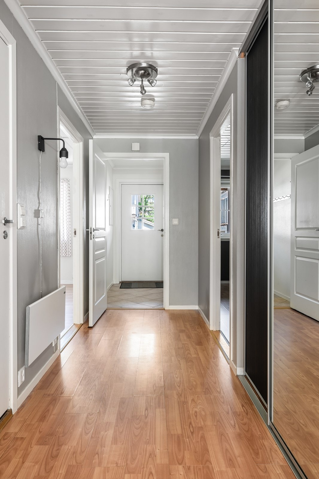 Fin, lys entré og tilliggende gang med praktisk skyvedørsgarderobe. Fra gangen er det adkomst til leilighetens stue, bad og to soverom. Galleribilde