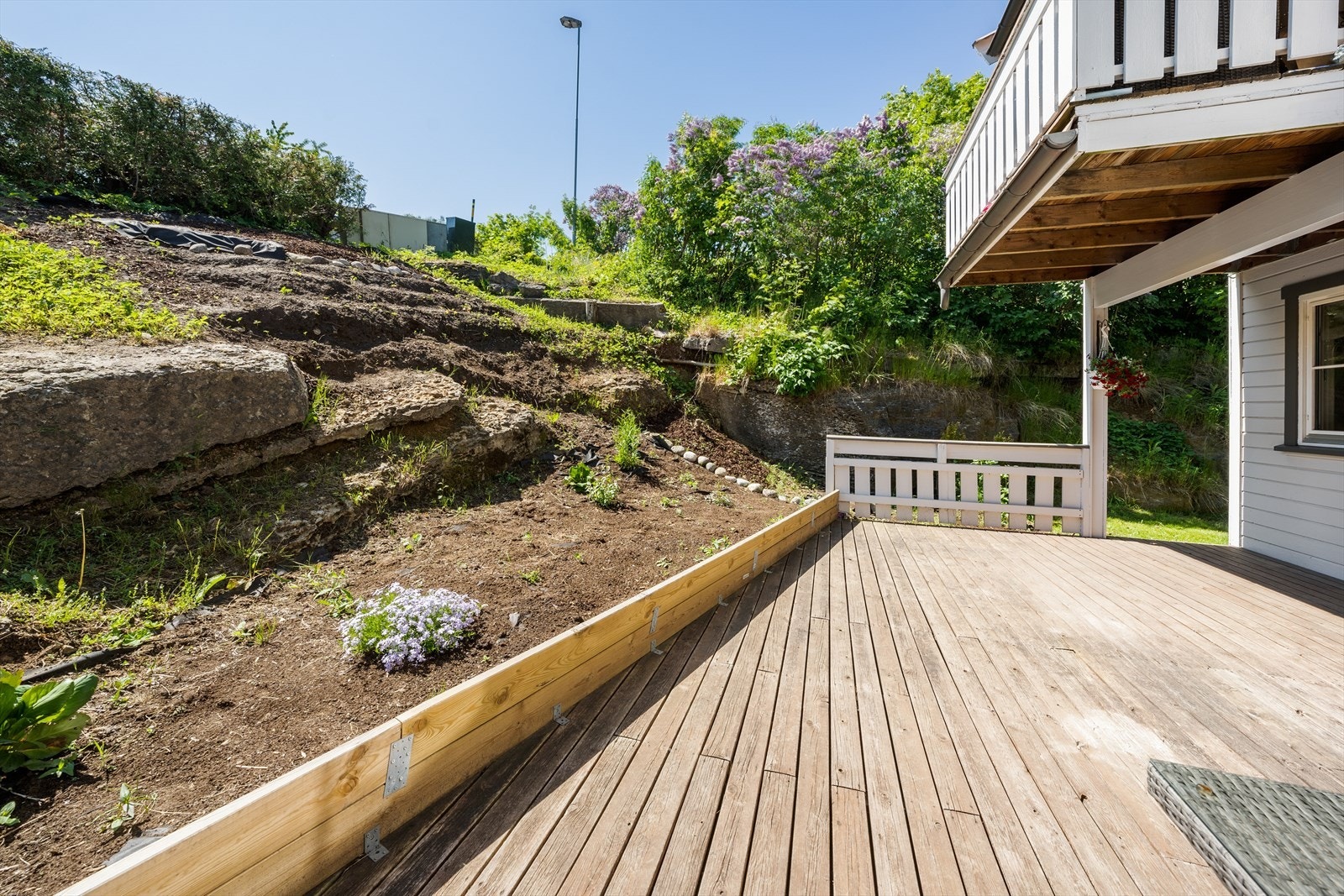 Deler av terrassen er overbygget av veranda tilhørende leiligheten over. Mot syd avgrenses terrassen av et blomsterbed. Galleribilde