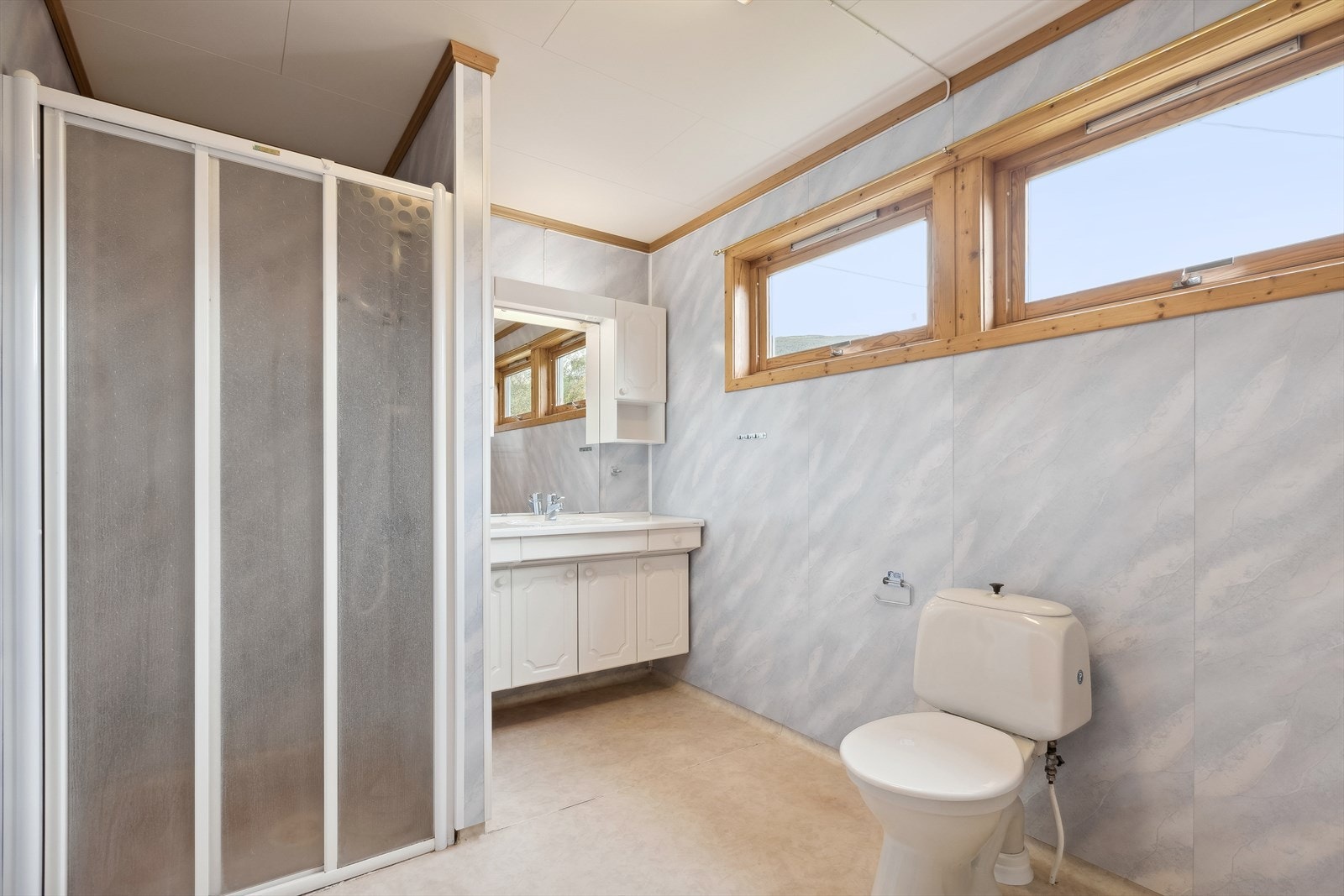 Stort bad/vaskerom med belegg på gulv, plater på vegger og i himling. Galleribilde