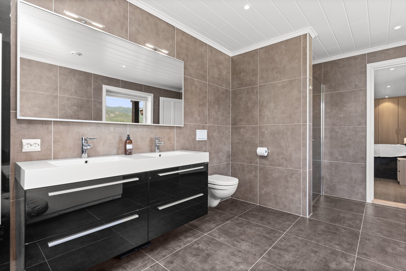 Baderom er flislagt med wc, dobbel servant, badekar og dusjnisje Galleribilde