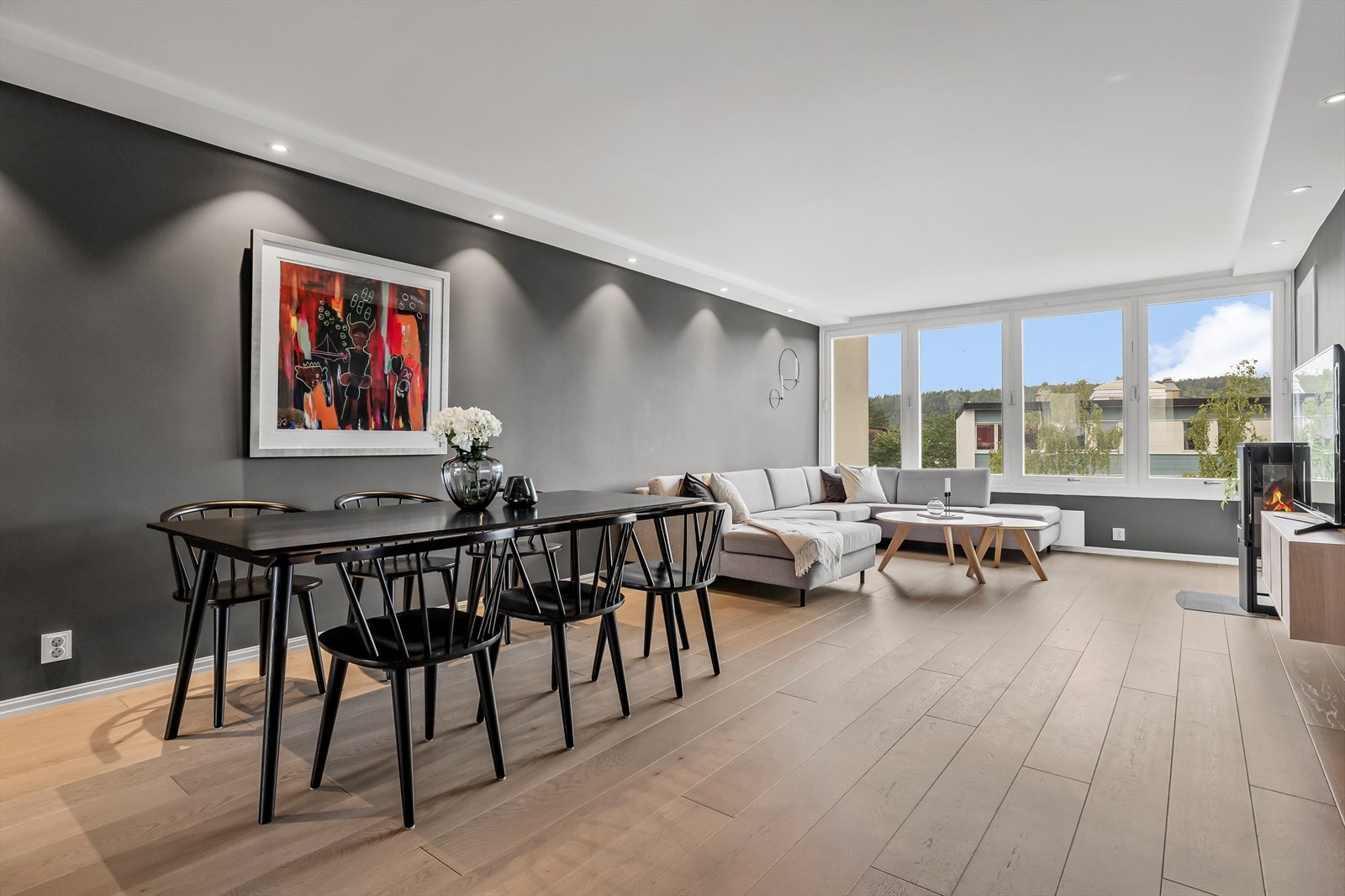 Stue og spisestue malt i moderne farger og peis som bidrar til ekstra hygge under kalde kvelder Galleribilde