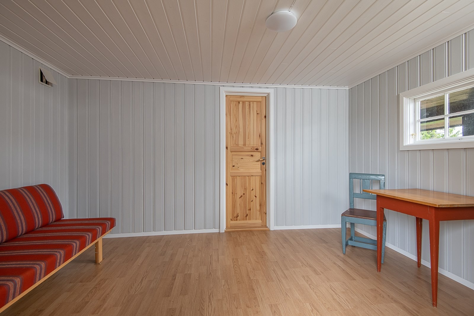 Disponibelt, isolert rom i uthuset. Vegger har malt panel. Dør inn til bod. Galleribilde