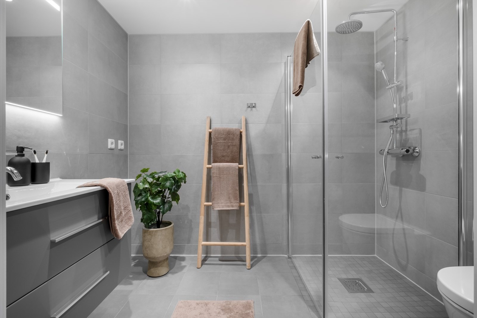 Pent, flislagt baderom med varmekabler i gulv og spotter i tak. Galleribilde