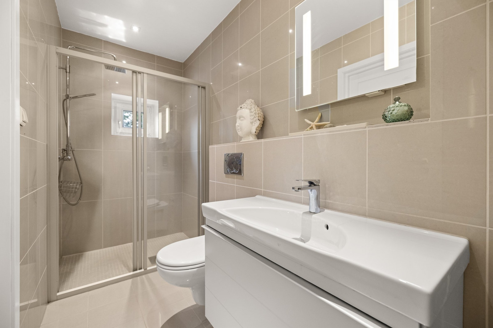 Bad - 2.etg: Flislagt gulv med gulvvarme og flislagte vegger. Servantskap med skuff i matt hvit utførelse og nedsenket servant i porselen med ett-greps armatur. Galleribilde