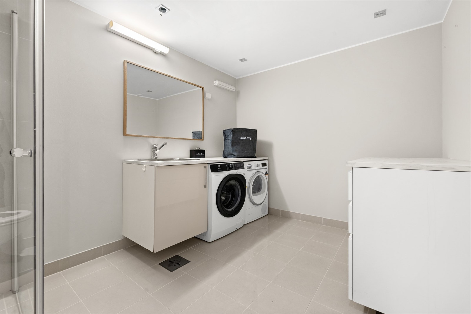 Bad/vaskerom: Servantskap med nedsenketutslagsvask i rustfritt stål med ett-greps armatur. Benkeskap med slette fronter i høyglans hvit utførelse og laminert benkeplate. Galleribilde