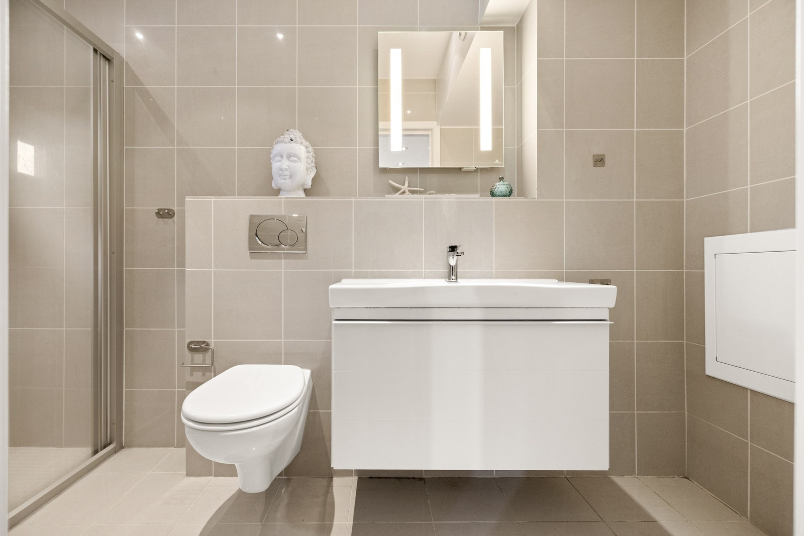 Speil med integrert belysning og dushjørne med skyvedør og to-greps armatur. Galleribilde