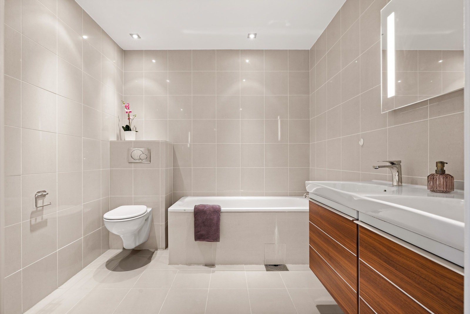 Bad - med adkomst fra gang: Servantskap med skuffer i treverk og speil med integrert belysning og stikkontakt på vegg over servant. Galleribilde