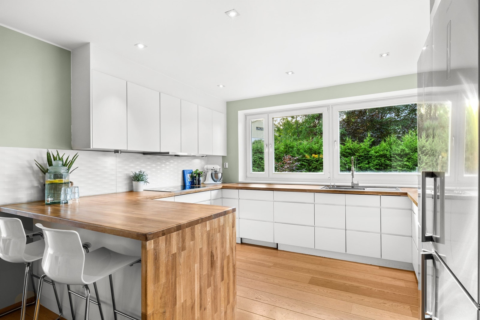 Benkeplater i treverk og nedsenket oppvaskkum i rustfritt stål med ett -greps armatur. Kitchenboard og stikkontakter på vegg mellom benkeplate og overskap. Galleribilde