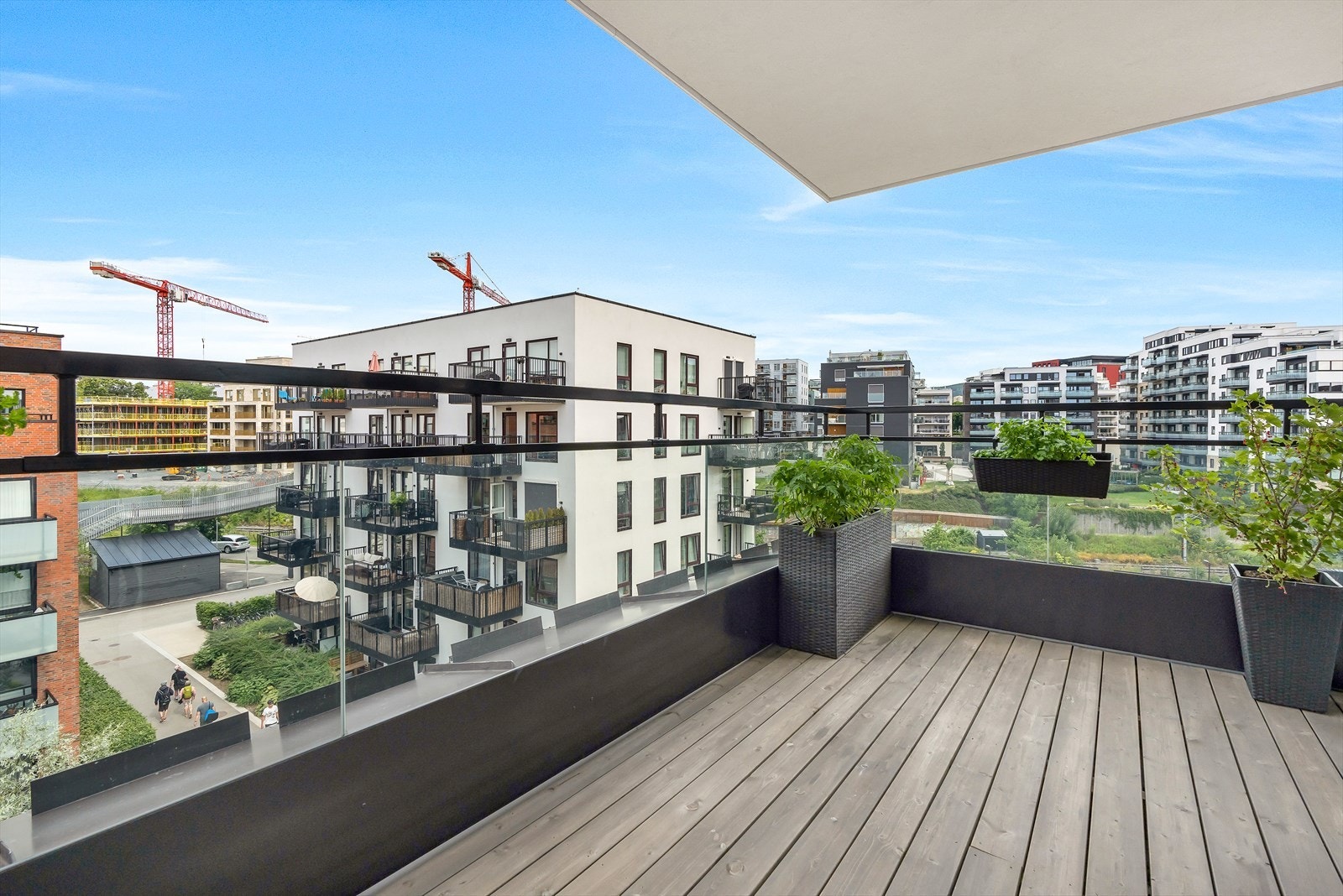 Overbygget vestvendt balkong på 9,5 m² med tredekke og glassrekkverk. Åpent utsyn og god avstand til byggene rundt. Galleribilde