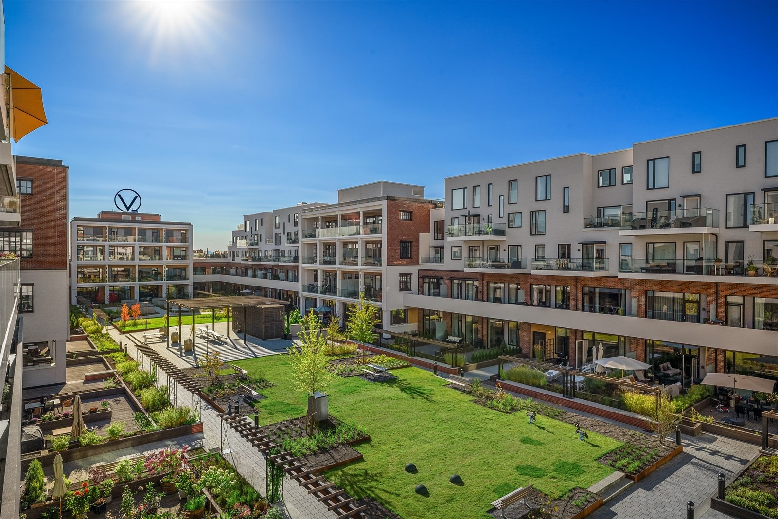 Pent opparbeidet og lukket atrium/bakgård med plen, plantekasser, benker, sittegrupper, bordtennis og pergola med langbord. Galleribilde