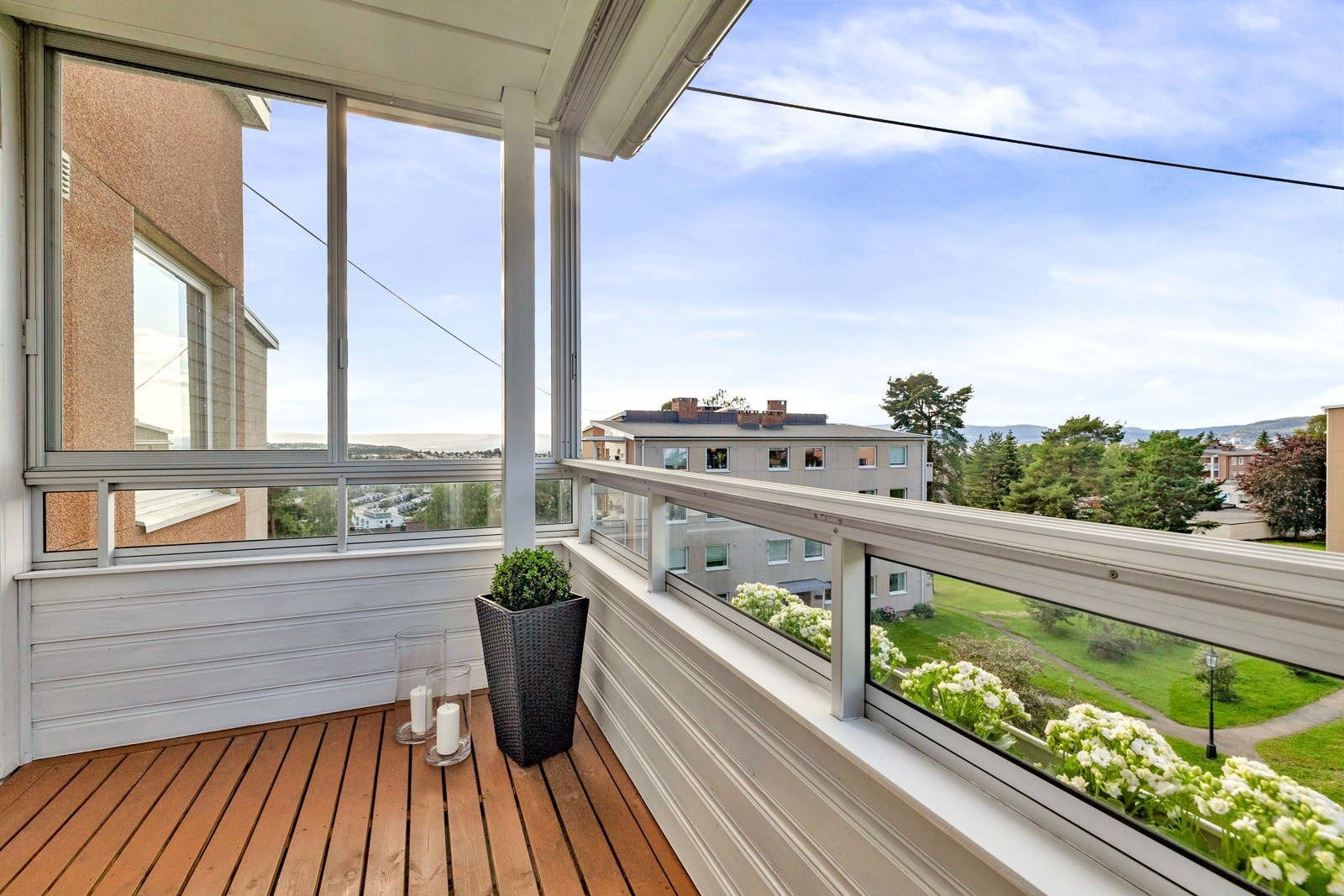 Balkongen har terrassebord på dekket, rekkverk i stål og glass Galleribilde