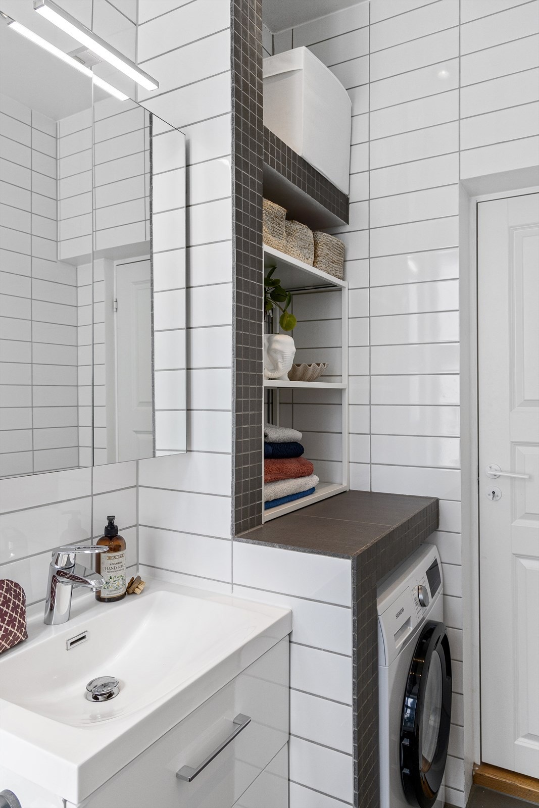 Praktisk plassbygd benk over vaskemaskin med hylleløsninger for lagring Galleribilde