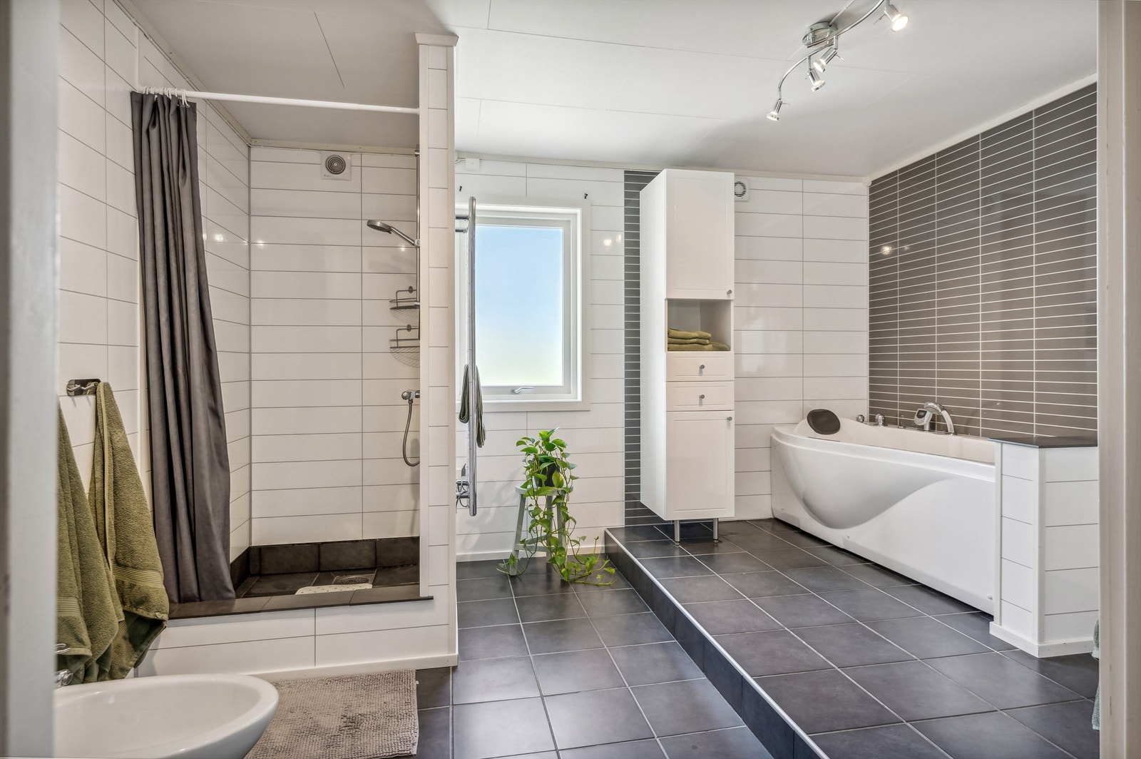 Badet er utstyrt med toalett, badekar, dusjnisje, toalett, skap og servantinnredning Galleribilde