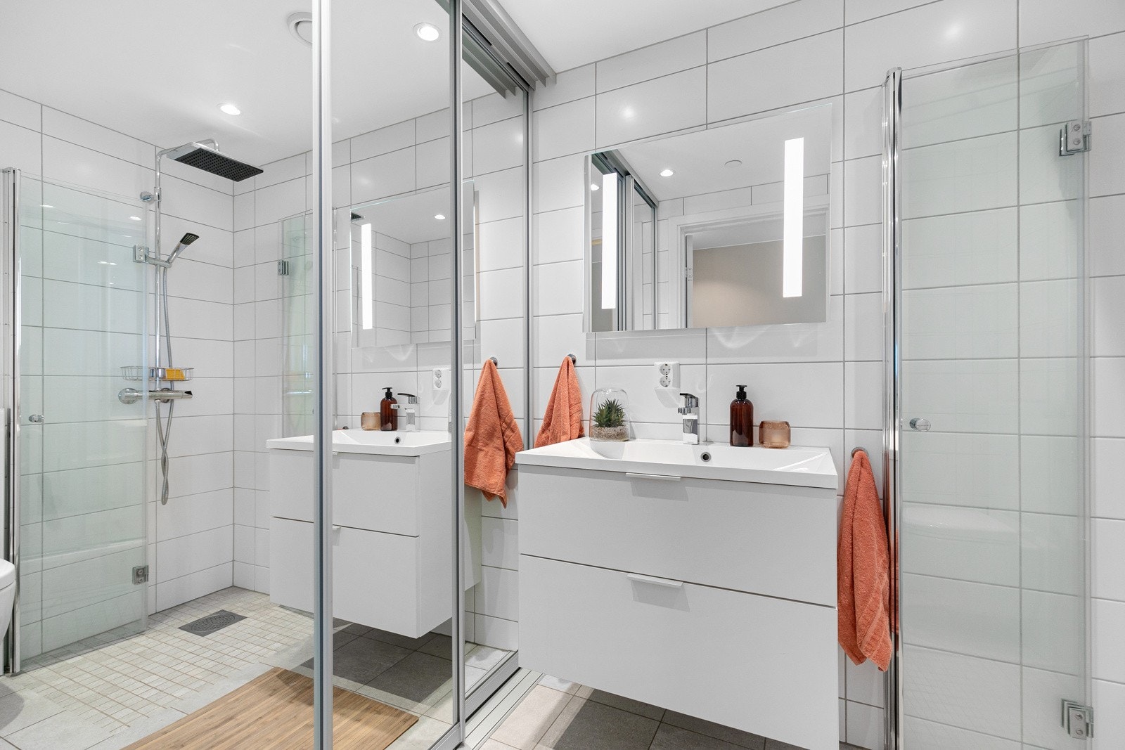 Leiligheten har to flislagte bad. På dette badet er vaskemaskinen pent skjult bak skyvedører. Galleribilde