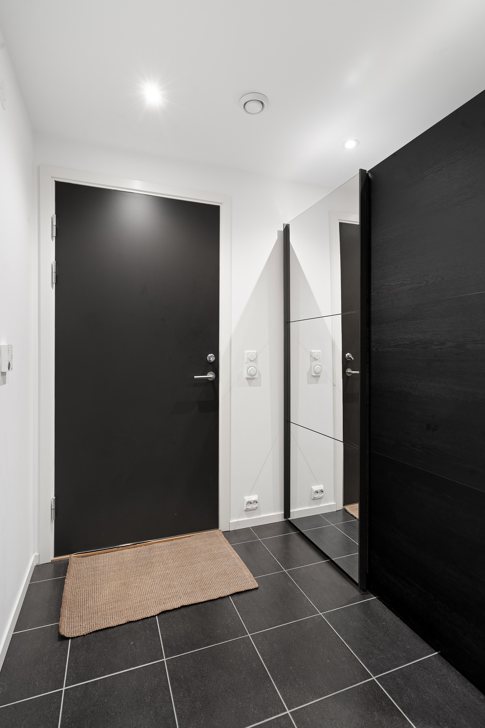 Flislagt gang med praktisk skyvedørsgarderobe med speil.