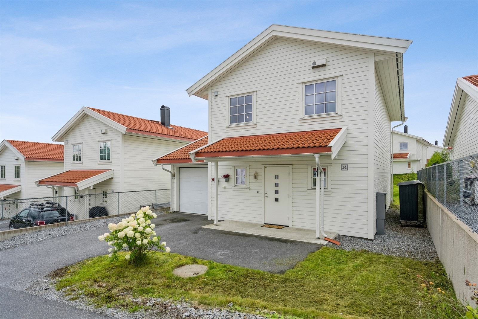På forsiden av huset er det gressplen, oppstillingsplass for 2 biler og garasje. Gjennomgang til terrassen og hagen både via tomten og via garasje og bod. Galleribilde