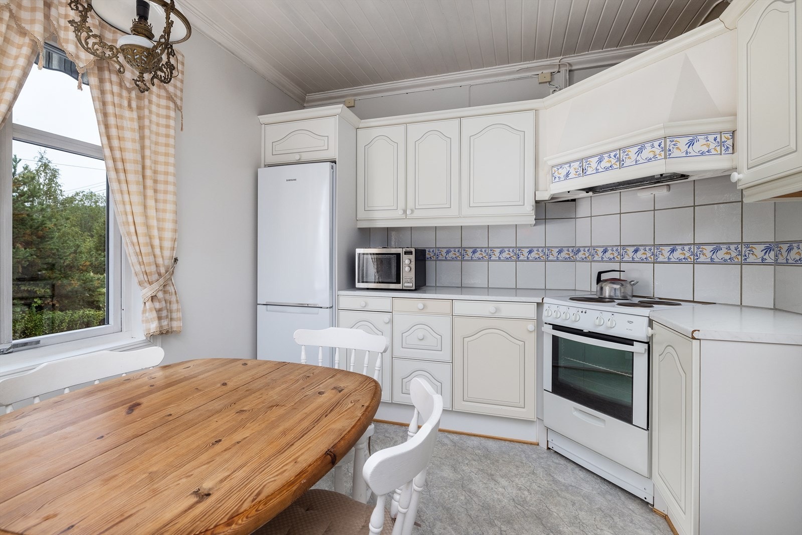 Kjøkkeninnredning med hvitmalte profilerte fronter og benkeplate i laminat. Galleribilde