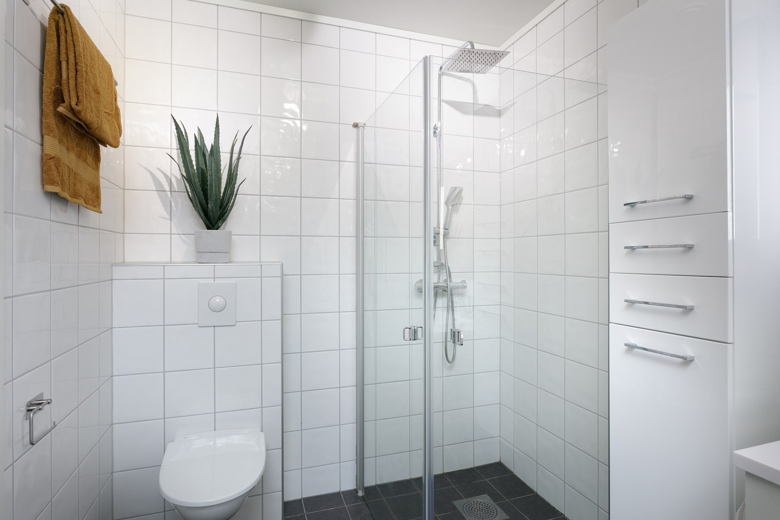 Badet er utstyrt med bl.a. vegghengt toalett, veggmontert dusj og glass veggmonterte dusjdører og baderomsinnredning. Galleribilde