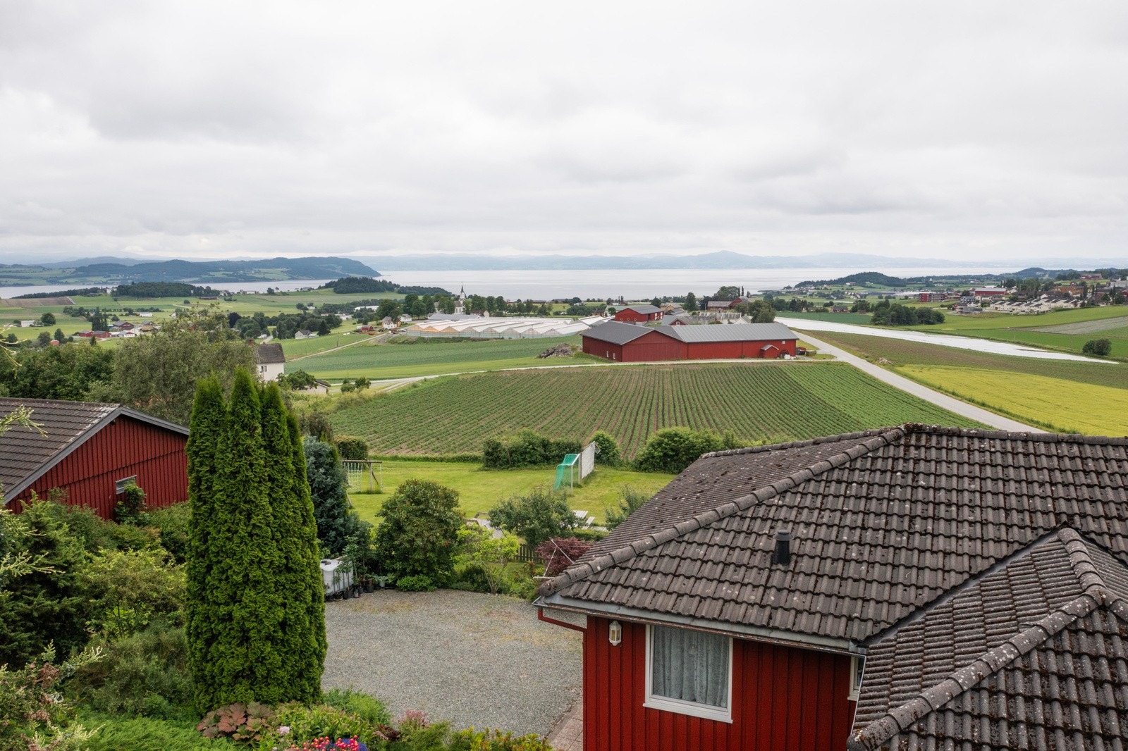 Dronefoto utsikt med bla felles lekeplass/ballplass og utsikten mot Frost og fjorden. Galleribilde