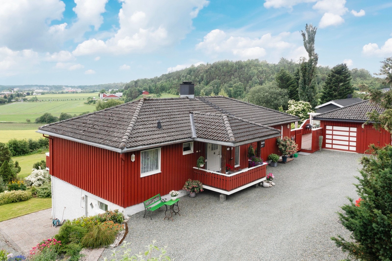 Dronefoto fasade og gårdsplass fremside. Egen inngang til vaskerom i sokkeletasje Galleribilde