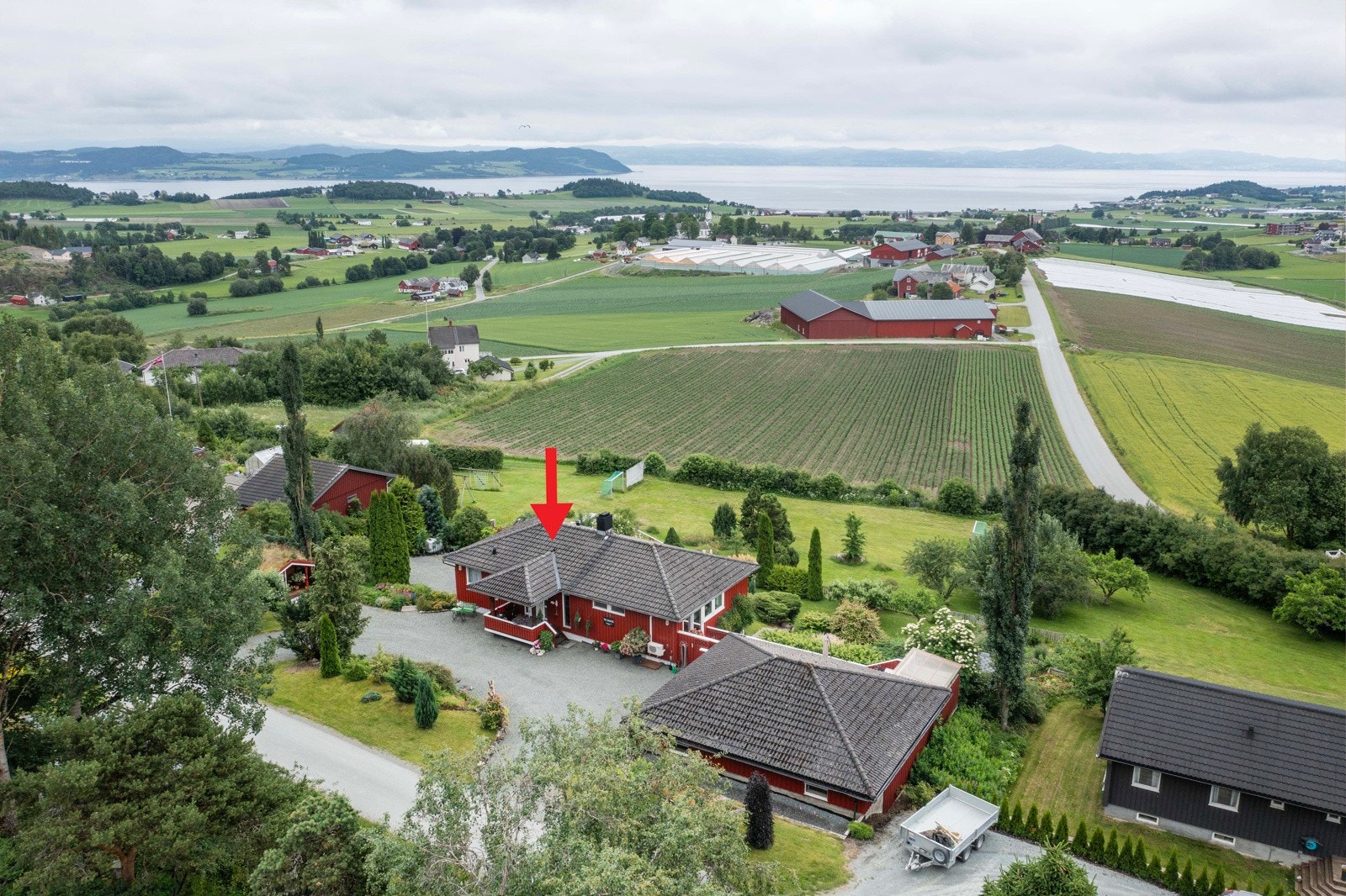 Dronefoto boligen og nærområdet. Boligen er markert med rød pil Galleribilde