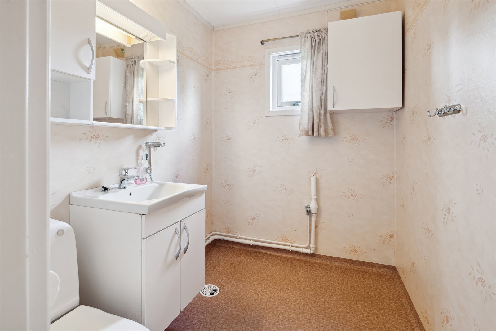 Bad med opplegg for vaskemaskin, belegg på gulvet og baderomstapet. Innredning med vask og gulvmontert wc Galleribilde