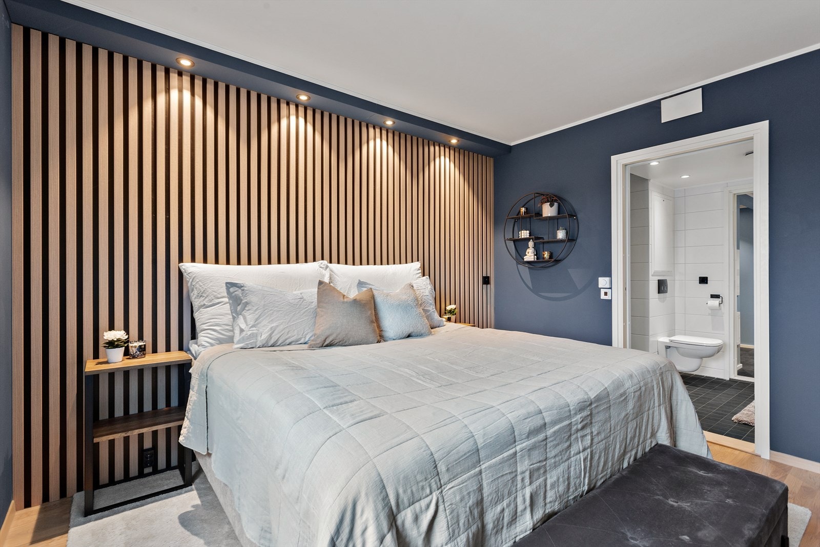 Soverommet har en vegg med stilige eikespiler og nedfelte downlights i overkant. Galleribilde