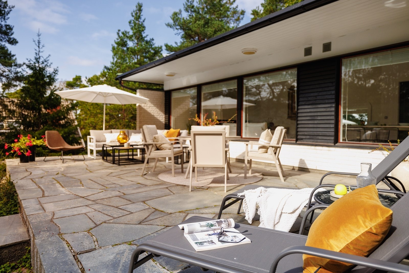 På sydsiden finner vi en stor skiferlagt terrasse, skjermet for innsyn av trærne, men likevel åpen takket være størrelsen. Galleribilde