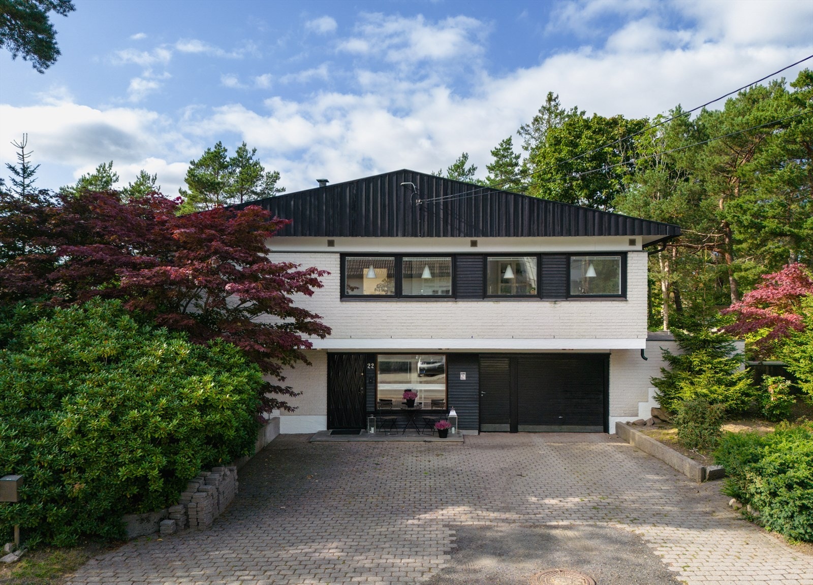 Boligen ligger delvis skjult fra veien bak furu, lønn og enorm rododendron - inntil den steinsatte gårdsplassen som åpner seg foran den østlige fasaden. Galleribilde