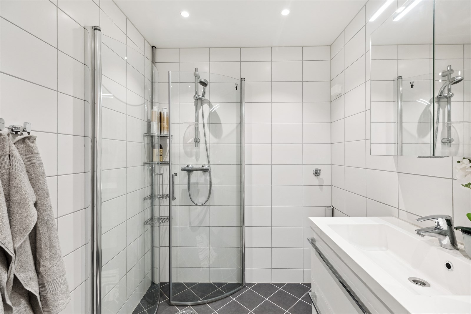 Delikat flislagt bad oppusset i regi av borettslaget i 2019, med varmekabler i gulvet og downlights i himlingen Galleribilde