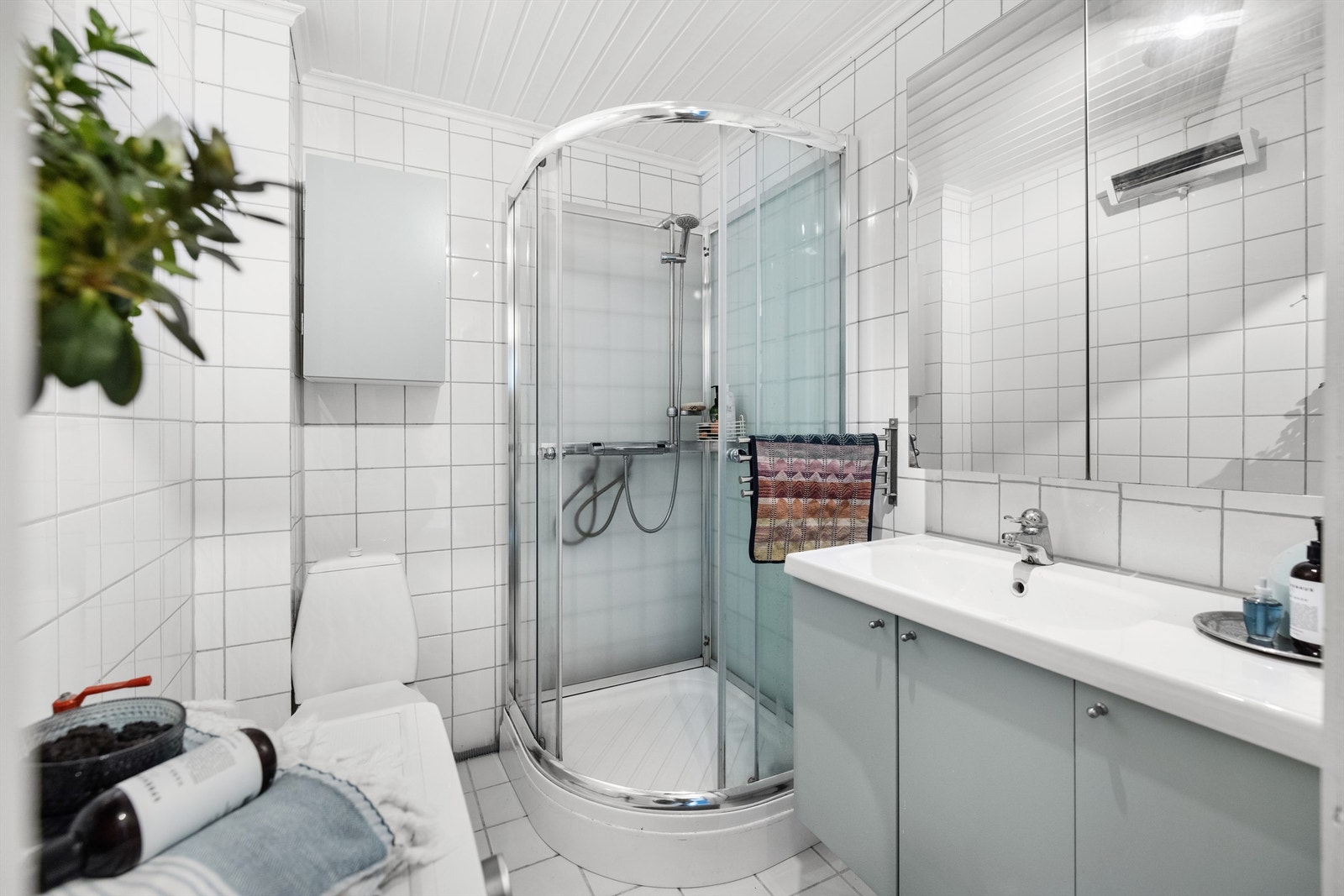 Badet er innredet med vegghengt servantinnredning med dører, ovenpåliggende servant med ett-greps armatur, og speilskap over servant, samt gulvstående toalett. Videre er det dusjkabinett med dusjarmatur tilkoblet veggmontert hånddusj. Galleribilde